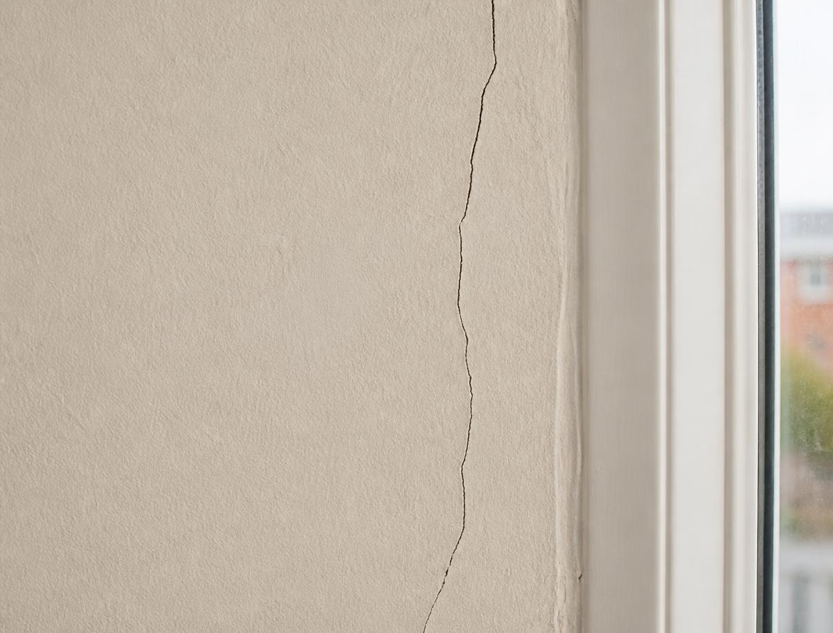 Haarscheur in een binnenwand naast een raamkozijn